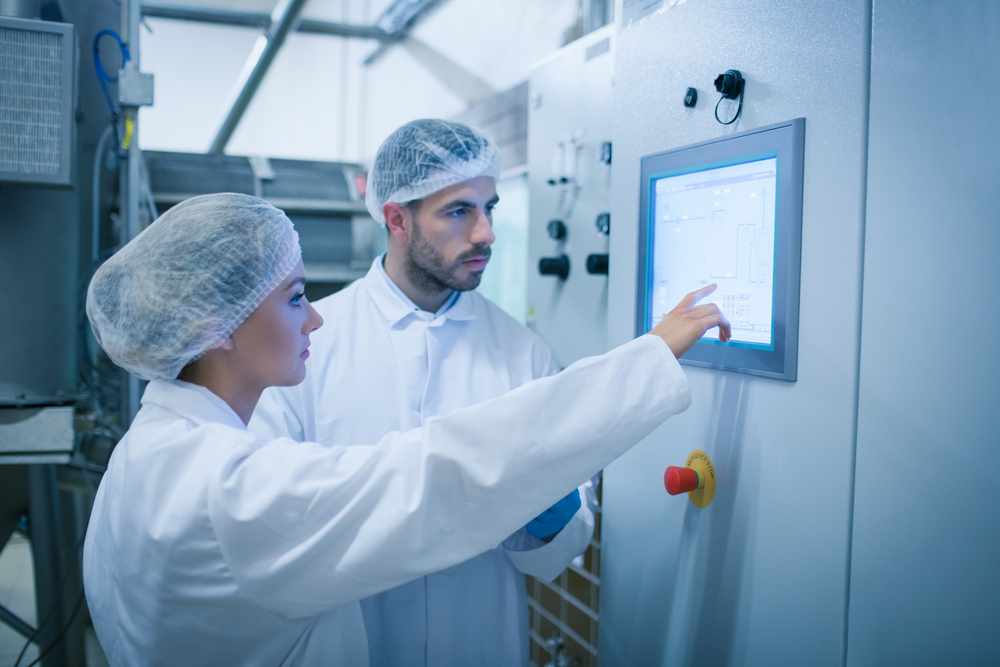 Manufacturing colleagues reviewing a digital control panel on the plant floor