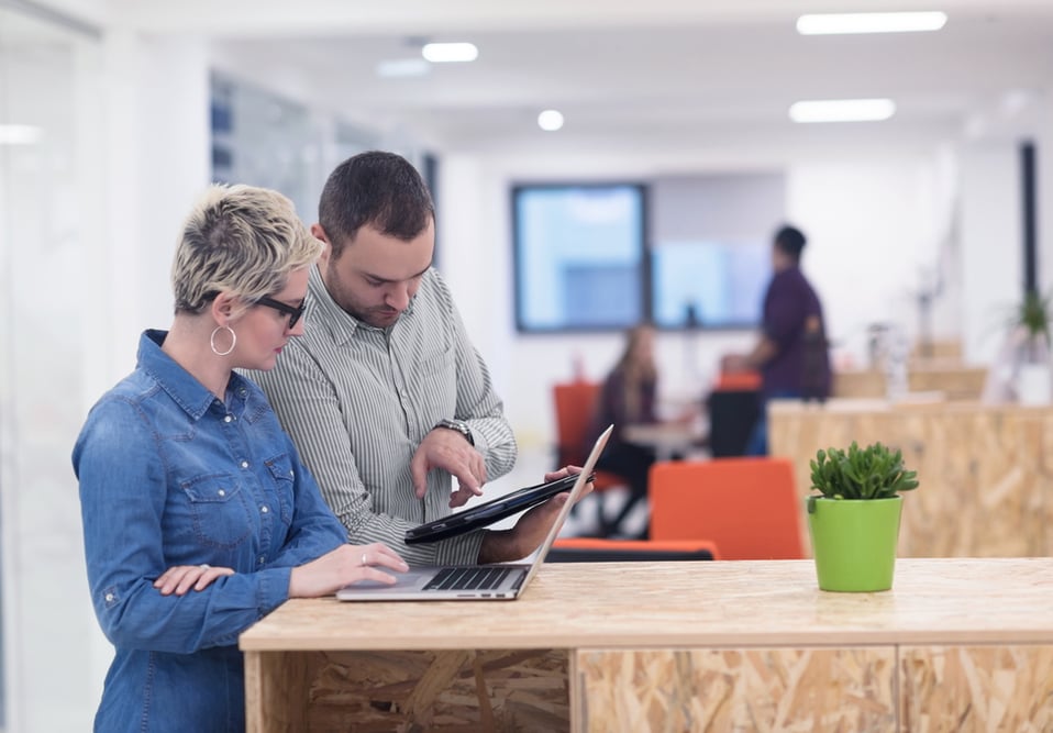 Business casual colleagues working through a workflow using a laptop and tablet